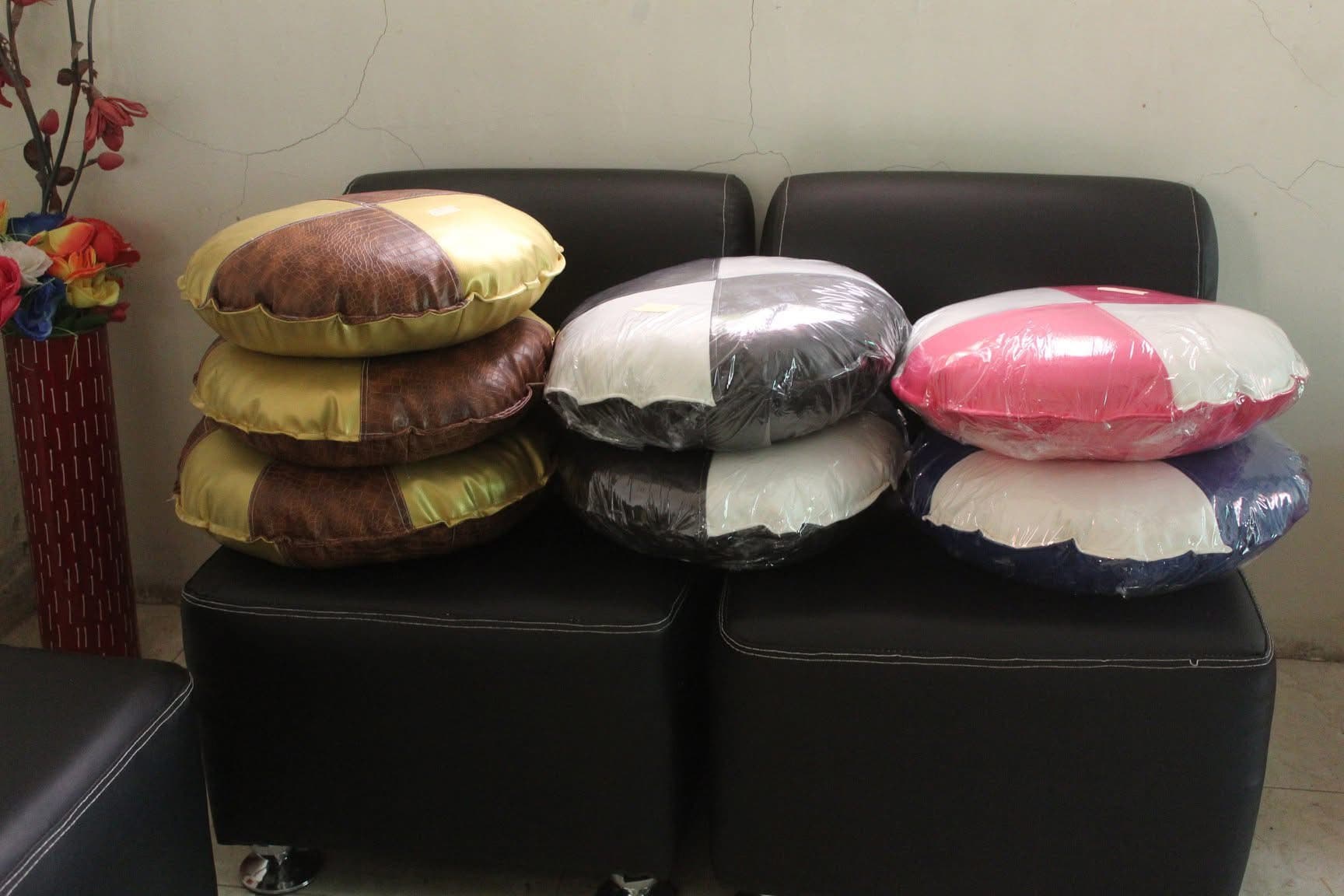 Assorted throw pillows stacked on an ottoman